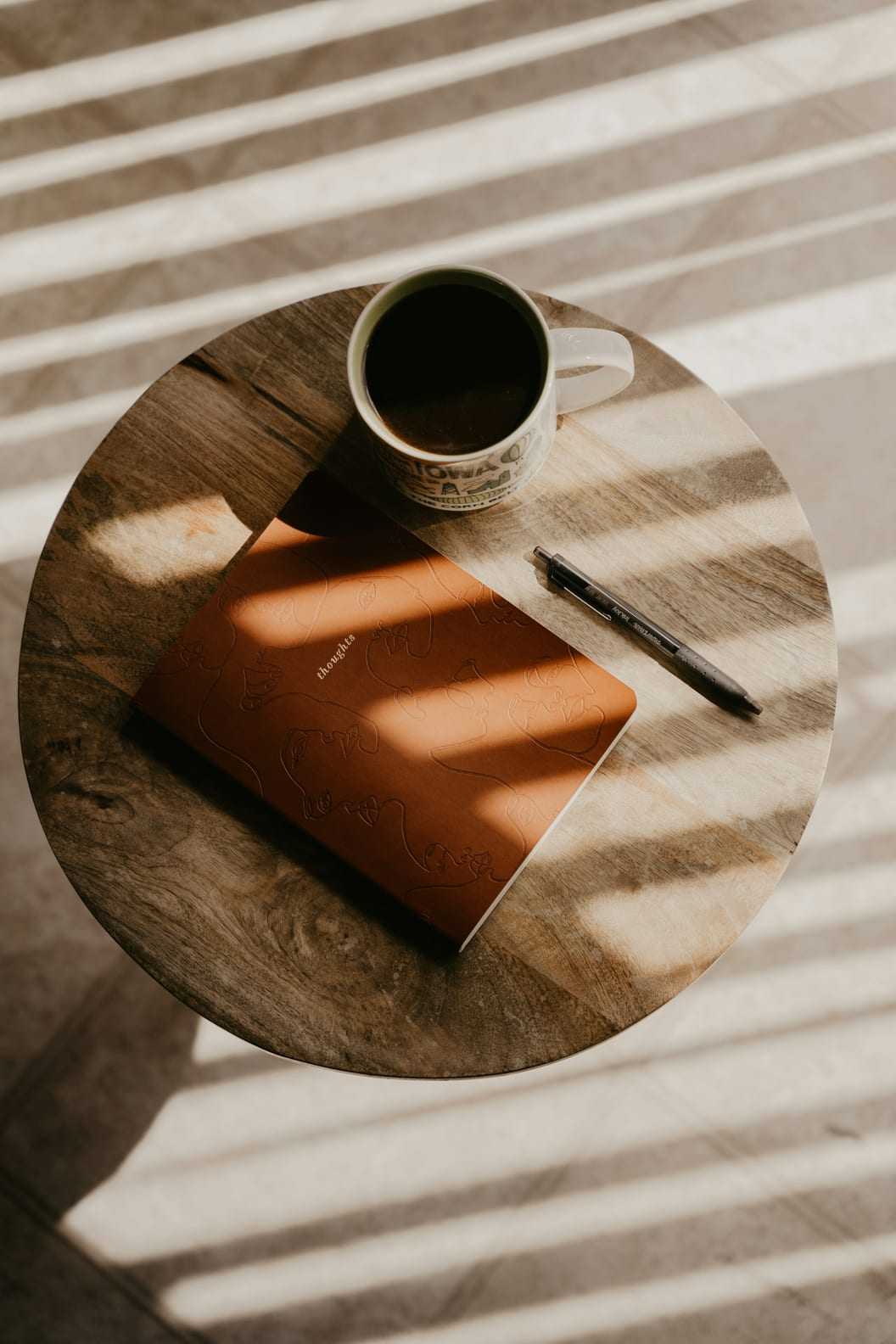 An open planning journal and pen resting on a wooden desk.